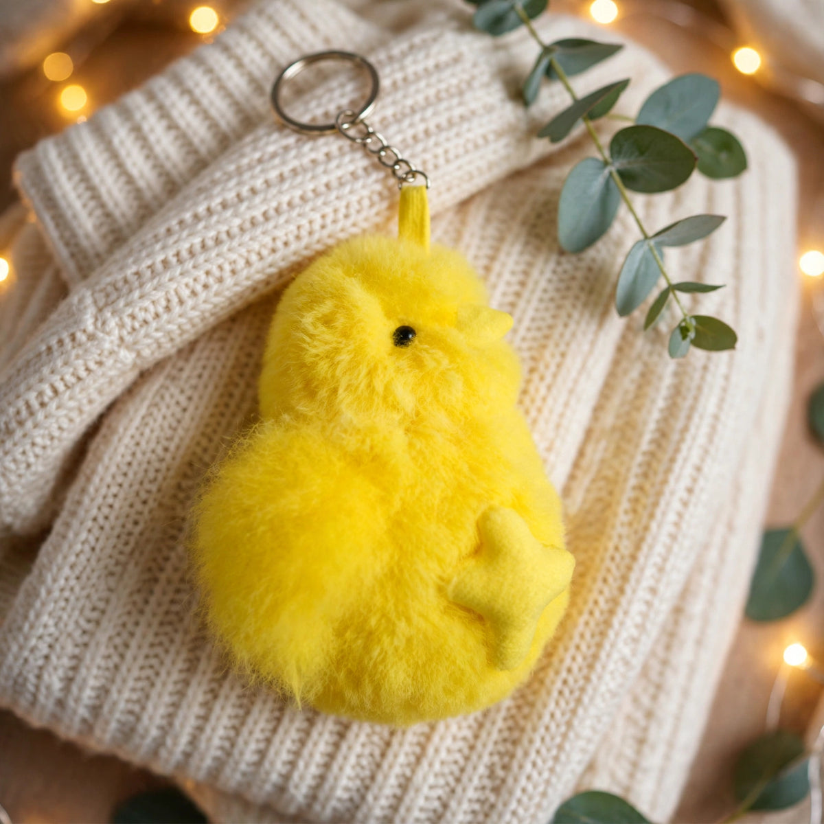 Yellow chick keychain on a cream knit sweater, a cozy holiday gift