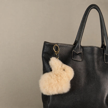 Beige alpaca fur bunny keychain as a bag charm on a black tote