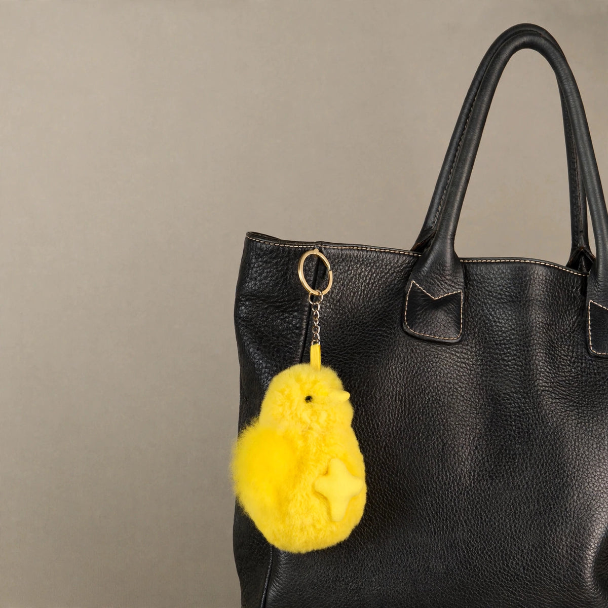 Yellow alpaca fur chick keychain as a bag charm on a black tote