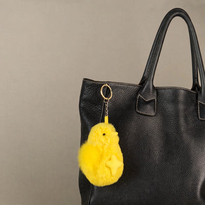 Yellow alpaca fur chick keychain as a bag charm on a black tote